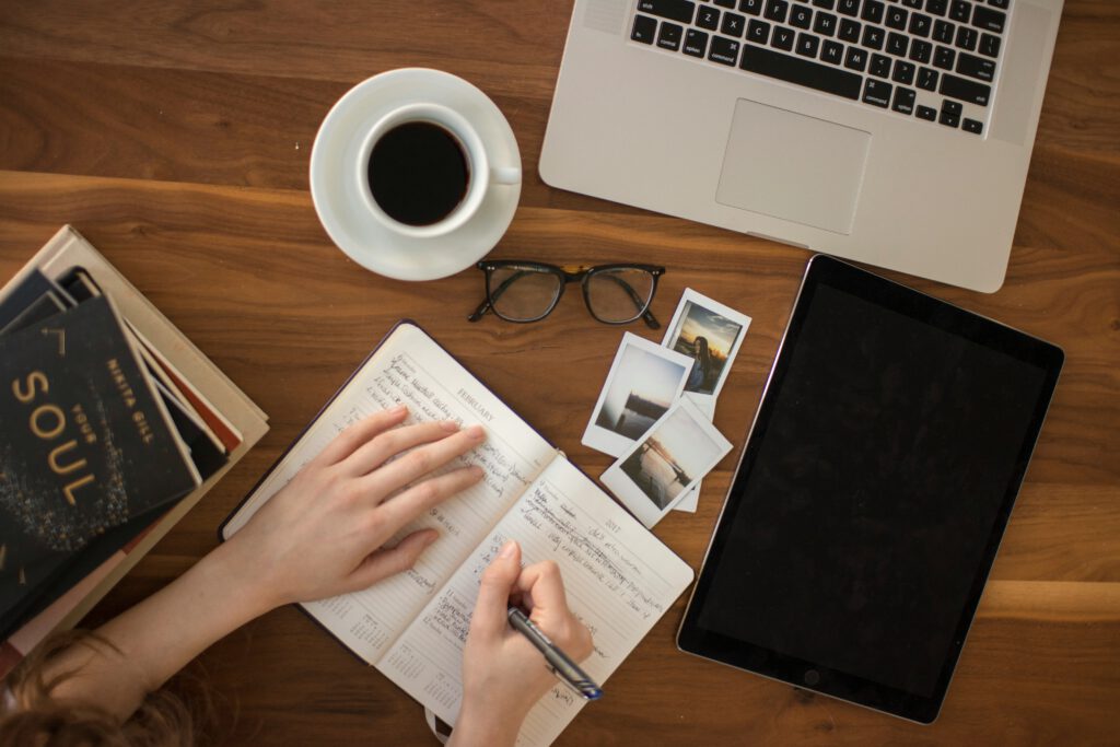 book that says Soul, a computer, and a journal and a cup of coffee on a wooden table