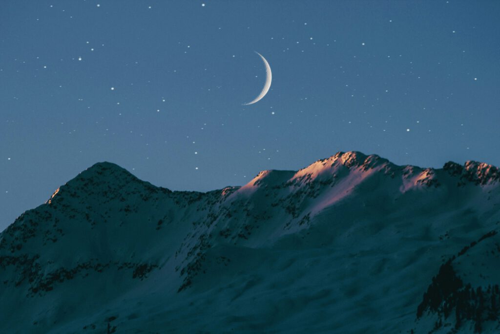 picture with crescent moon over the top of a  mountain with snow